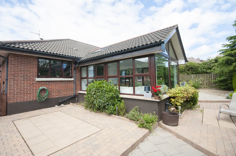 Sunroom extension on a modern bungalow with a low maintenance patio rear garden